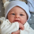Lalka Reborn jak prawdziwy noworodek leżąca w otulaczu z uszami królika