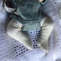 Zbliżenie na gumowe nóżki i podkolanówki śpiącej lalki niemowlę Reborn 49cm